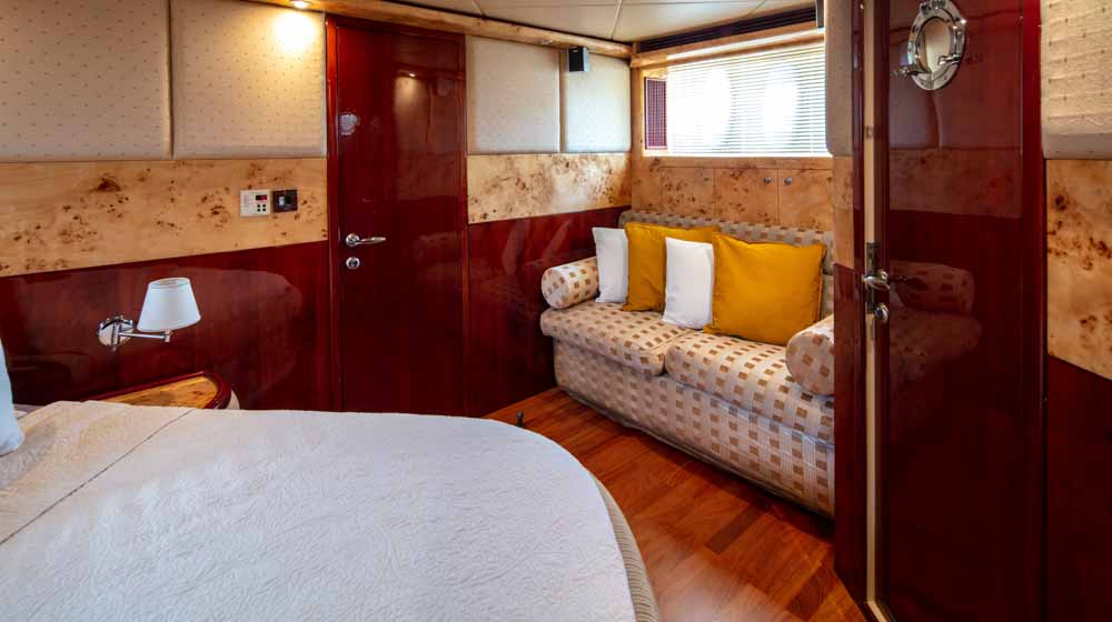 yacht stateroom with classic interiors, queen size bed, bedroom couch, large window